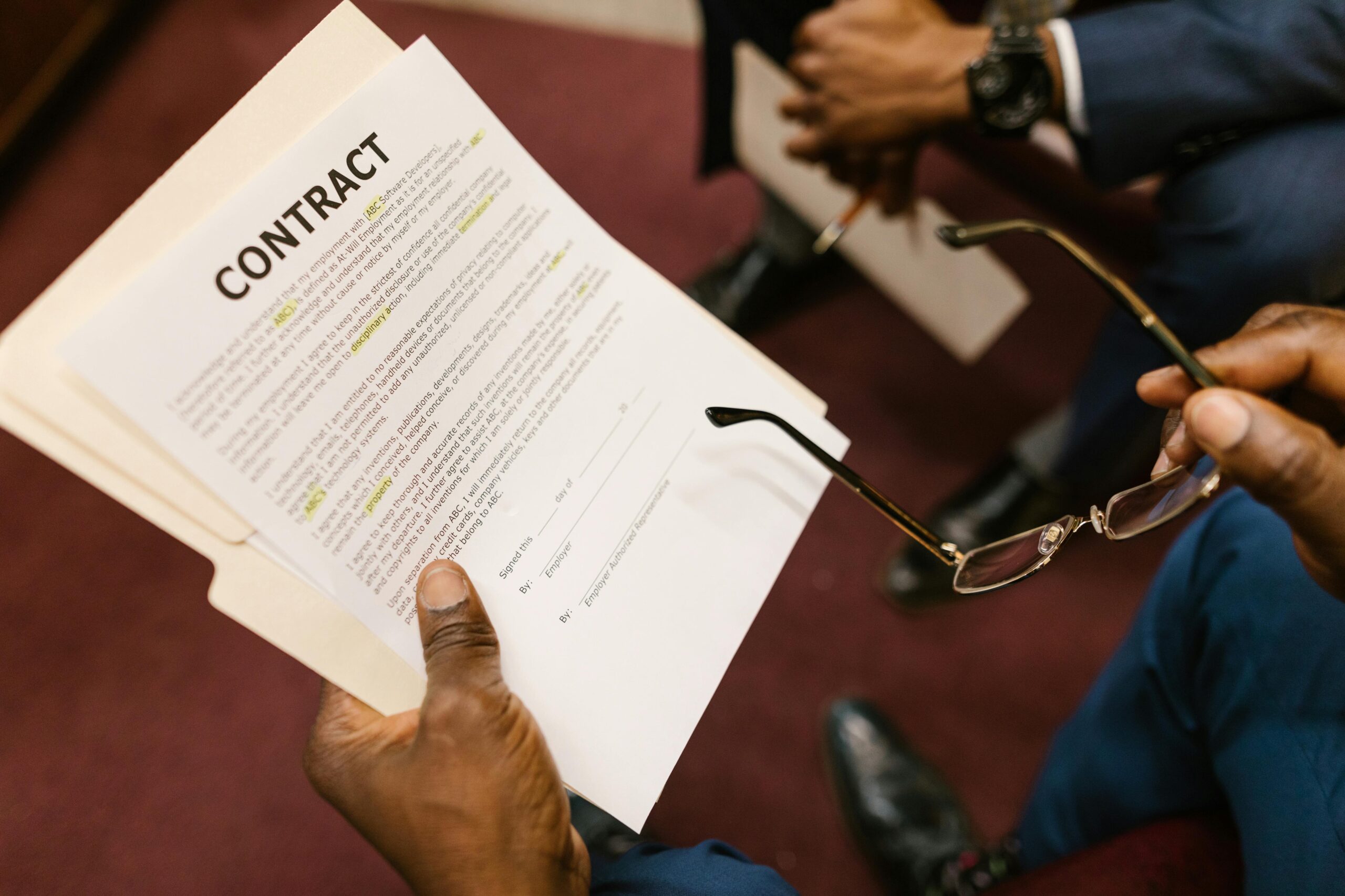 Closeup of hands holding glasses reading legal document labeled ‘Terms and Conditions’.